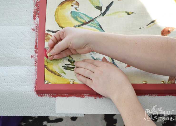 How to make a covered bulletin board with paint, fabric and brass upholstery tacks.